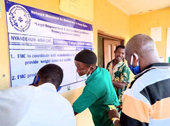 Men looking at poster "legal empowerment & accountability for effective healthcare delivery"